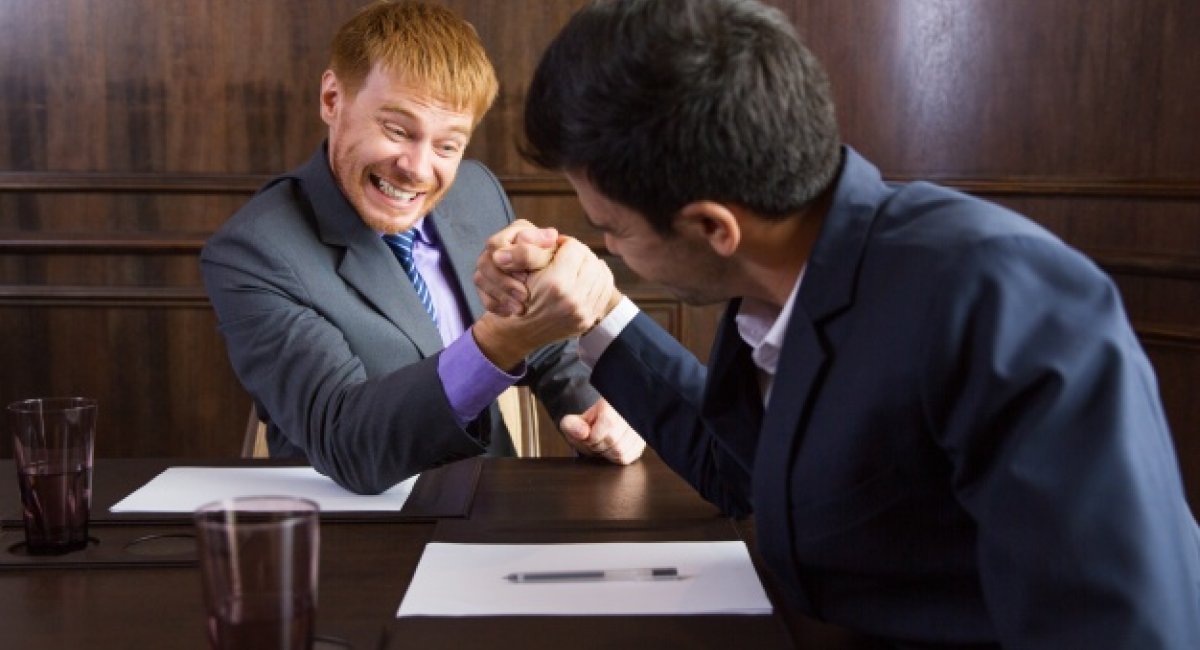 Two men in business suits arm-wrestling.