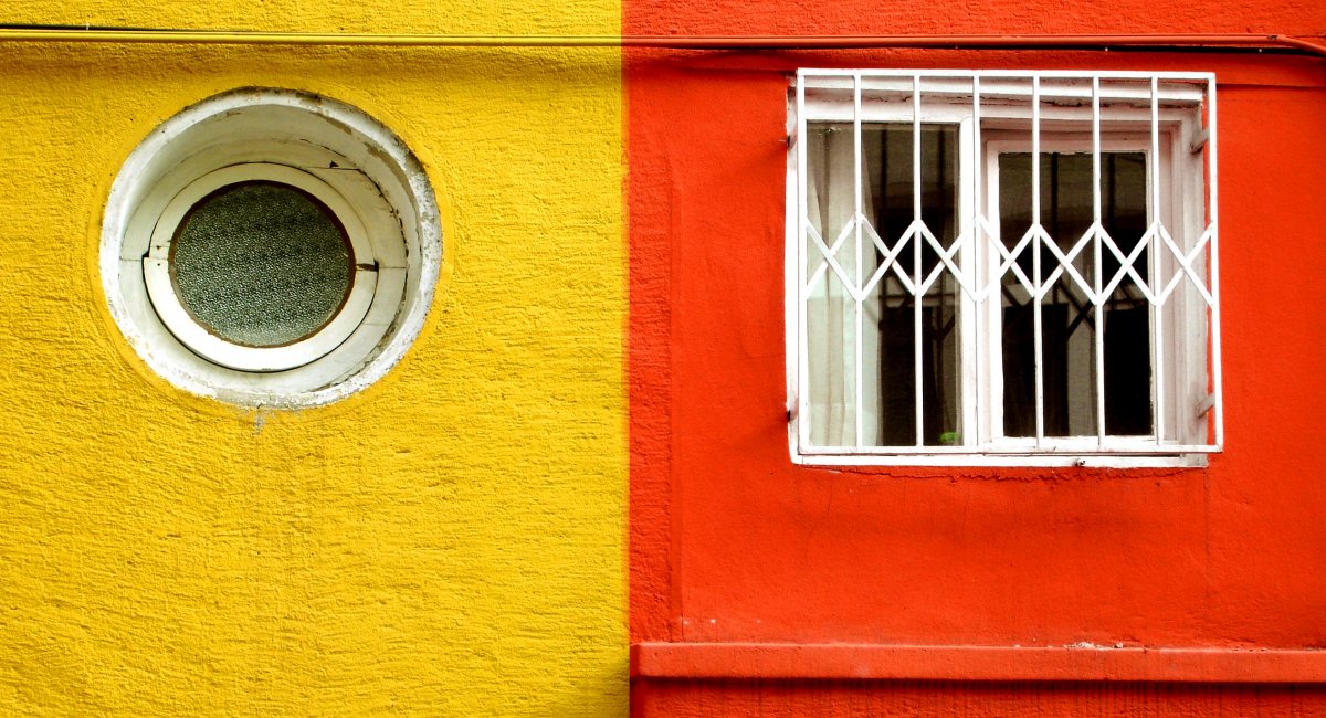 wall with two colors, circular window on yellow half, square window on orange half