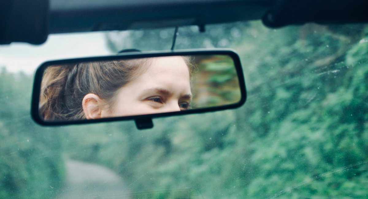 Review! Woman's face in the rear view mirror of a car