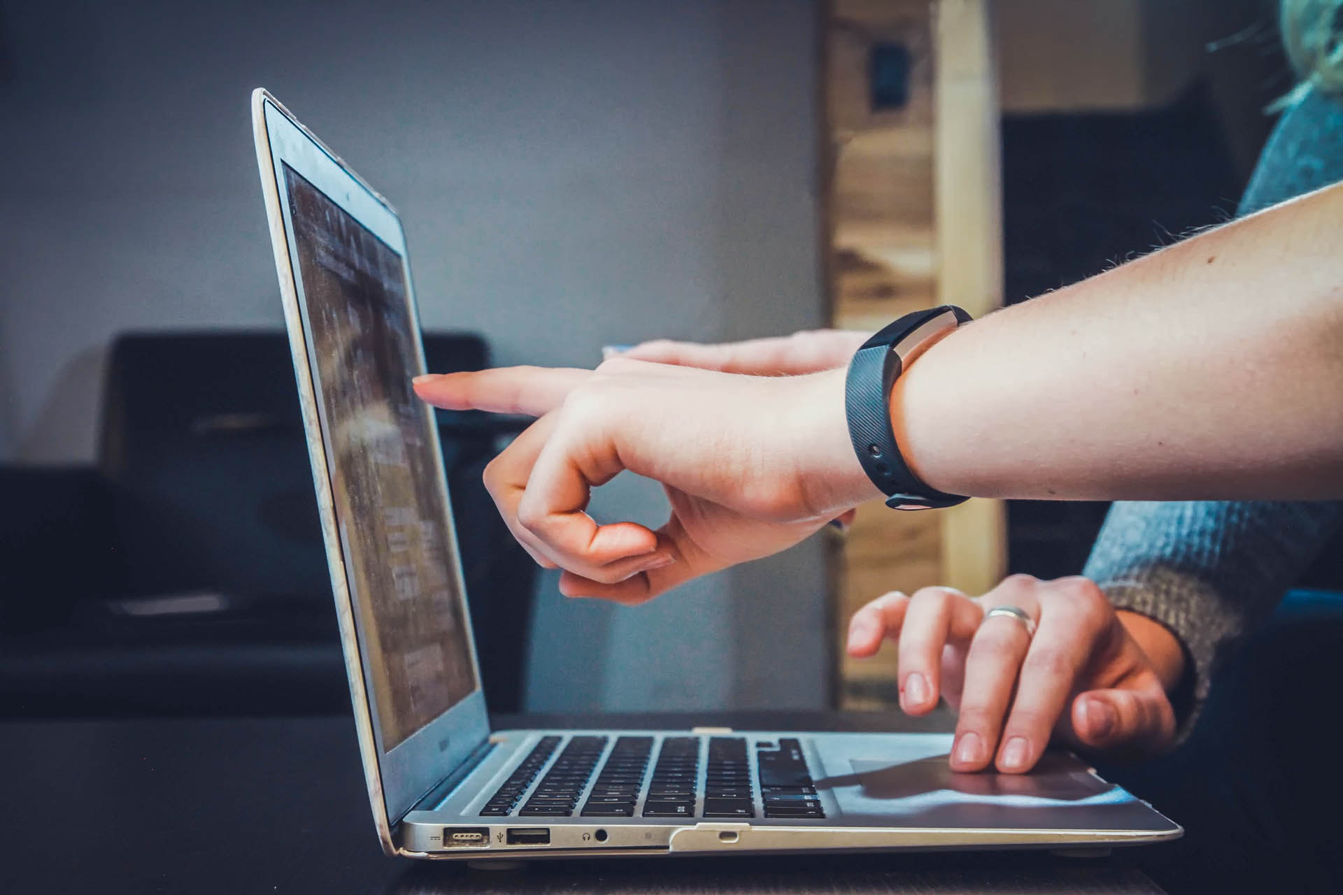 White person's hand pointing at a graph on a laptop screen 