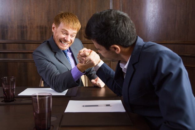 Two men in business suits arm-wrestling