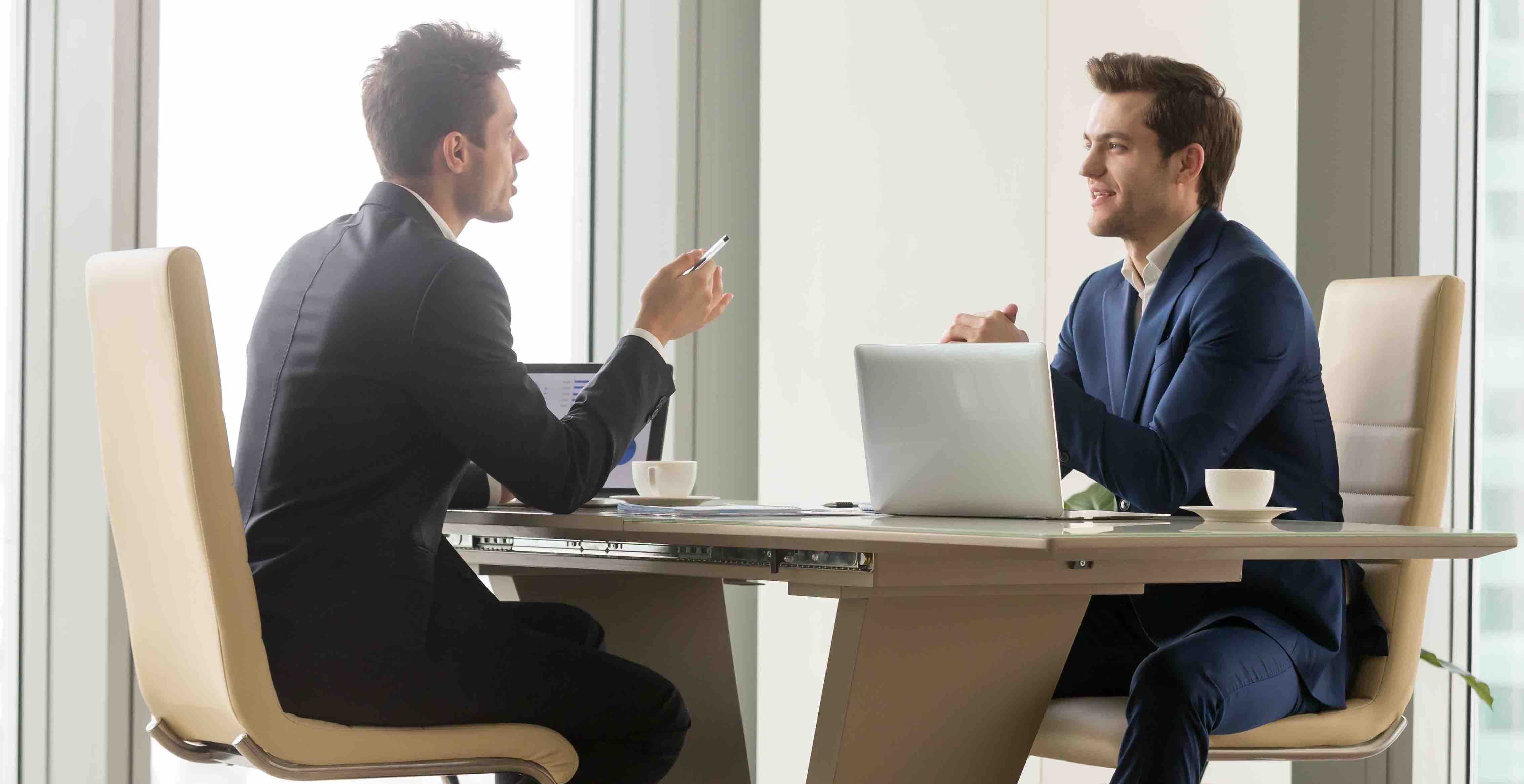 Two businessmen having a discussion at a table.