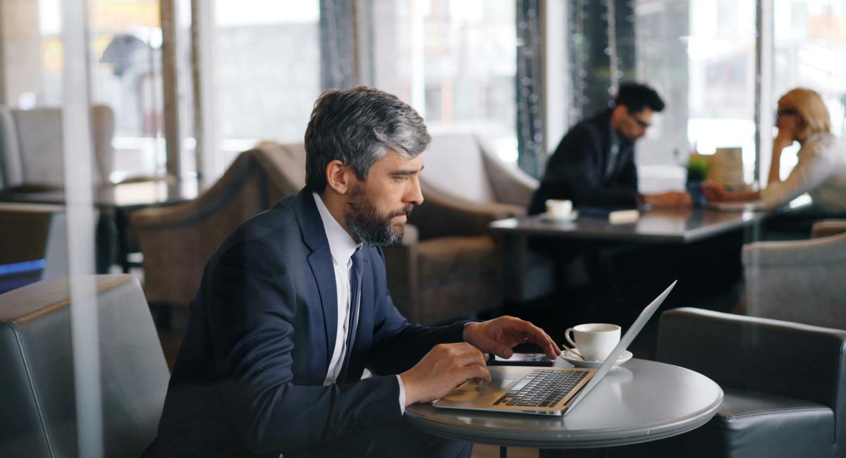 A man in a suit sitting at a table with a laptop