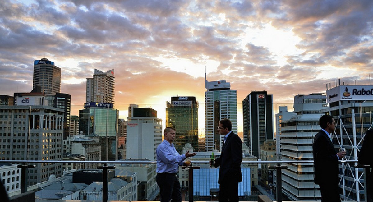 Two men talking on balcony cityscape in background