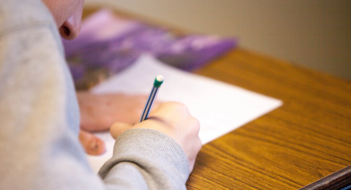 The hands of a person writing with pen and paper.