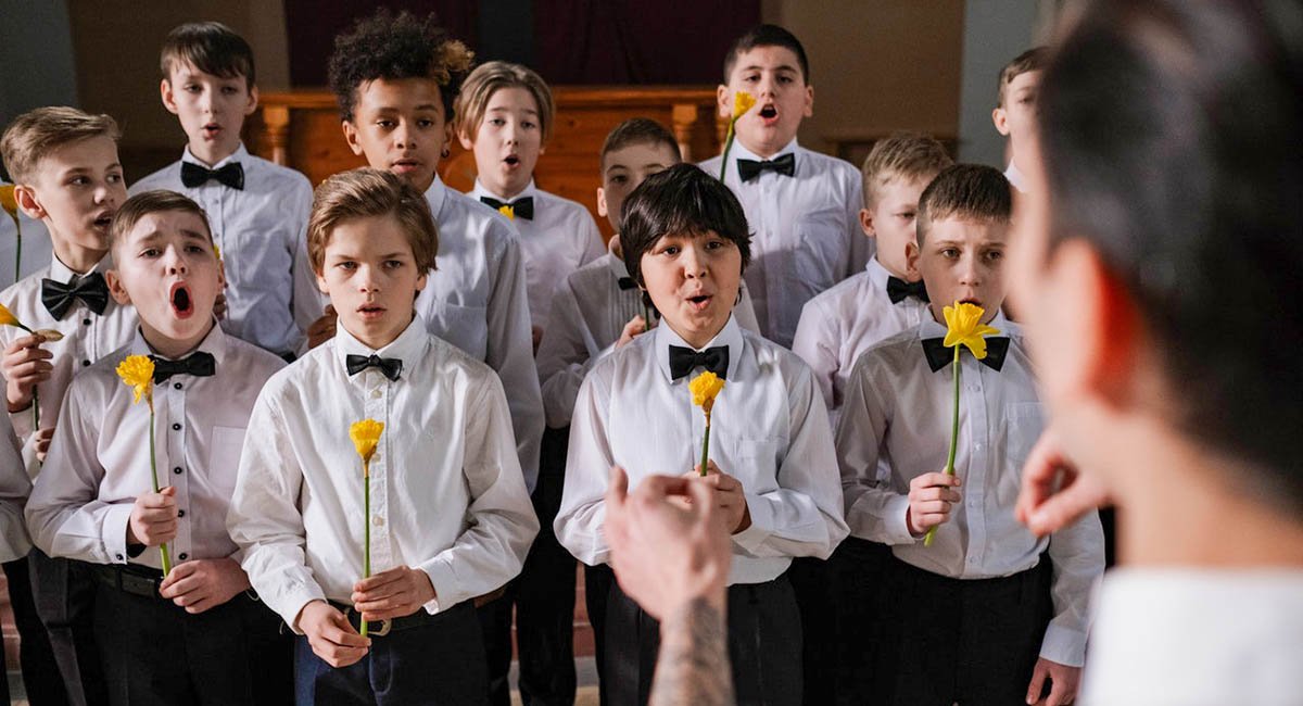 Young boys singing in chorus with yellow flowers