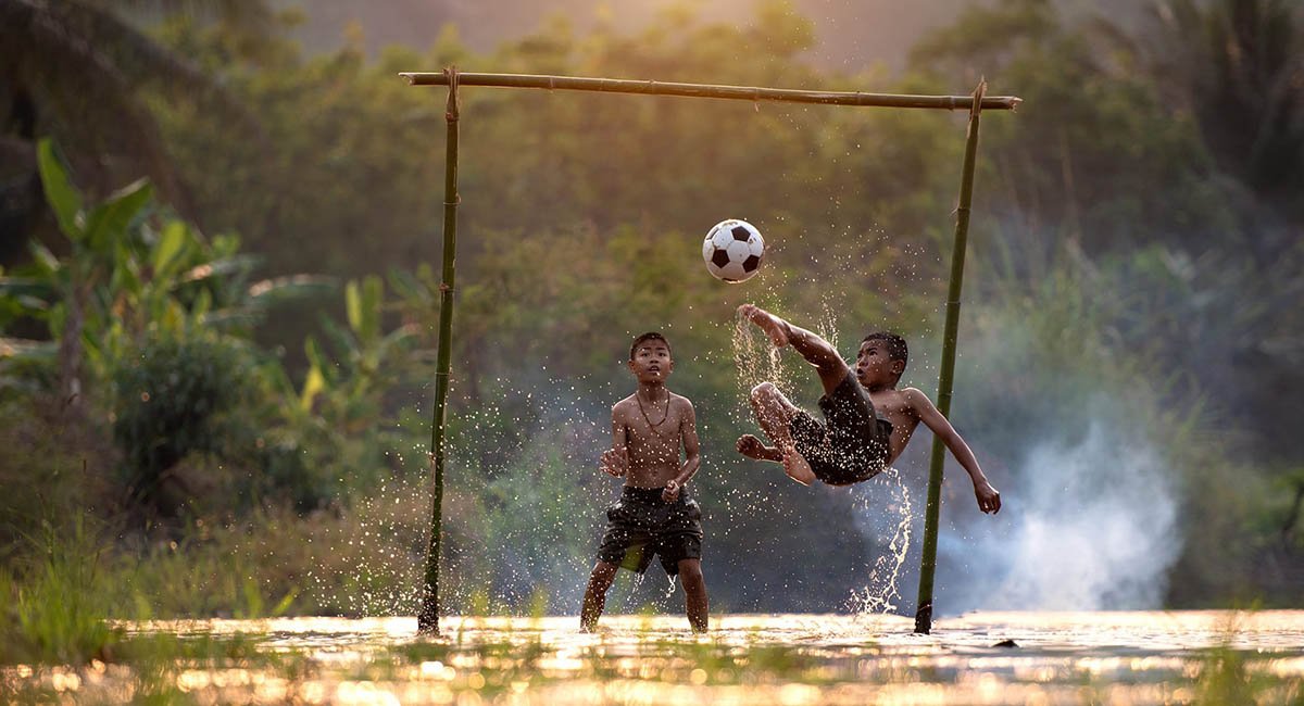To Vietnamese boys playing soccer splashing water